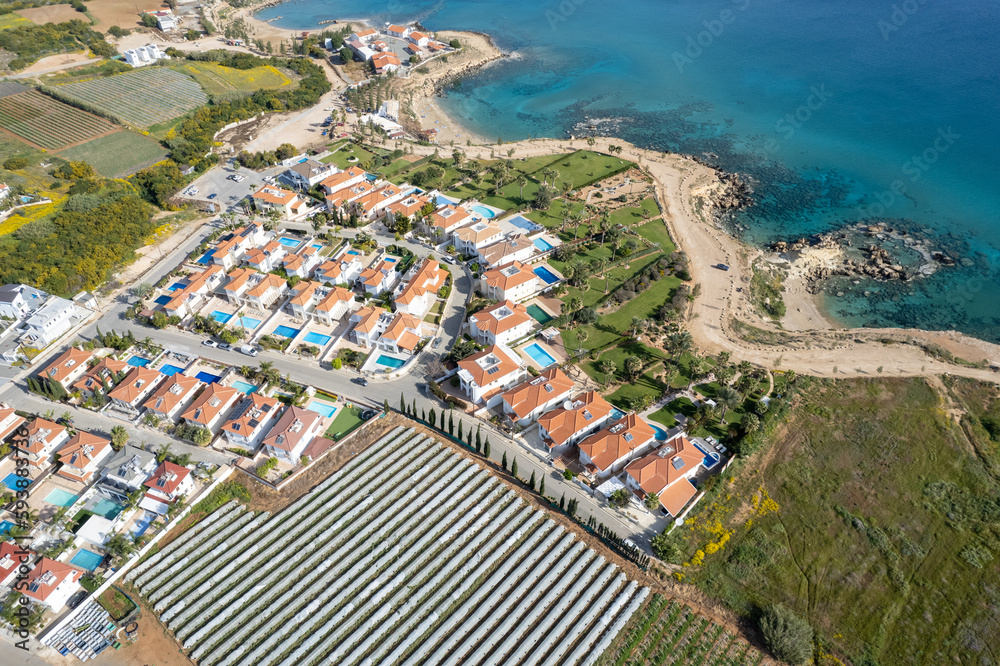 Drone aerial of holiday village with luxury houses at an idyllic rocky coast. Summer vacations at the sea.