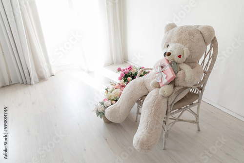 large stuffed toy in a chair with gifts and flowers in the room photo