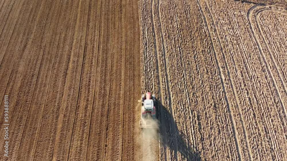 Tracteur qui roule dans un champ sec avec la poussière.