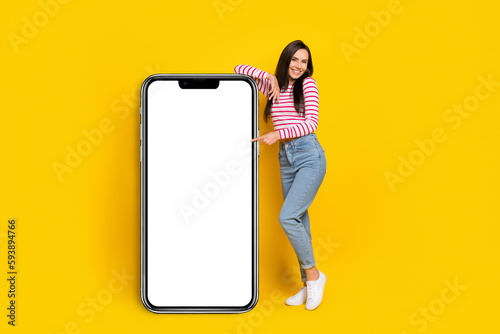 Photo of pretty lady present big placard board wall empty space recommend cool offer proposition isolated on yellow color background