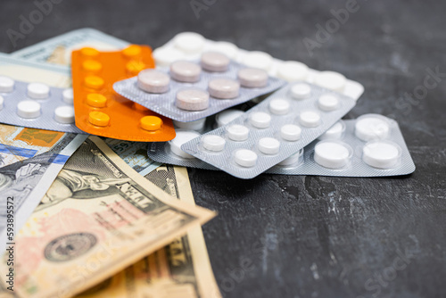 Blister packs with tablets or pills, antibiotic, painkiller or drugs and money, US dollar banknotes, expensive medicine and healthcare concept, close-up view