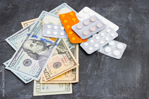 Blister packs with tablets or pills, antibiotic, painkiller or drugs and money, US dollar banknotes, expensive medicine and healthcare concept, close-up view