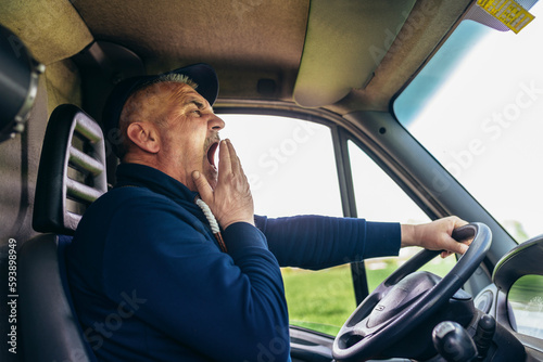 Mature truck diver feeling tired and yawning during the ride. photo