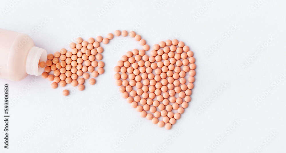 Pink pills in the shape of heart on white background. Vitamins, supplements for the heart.