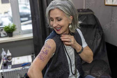 Long-haired woman looking at her new tattoo photo