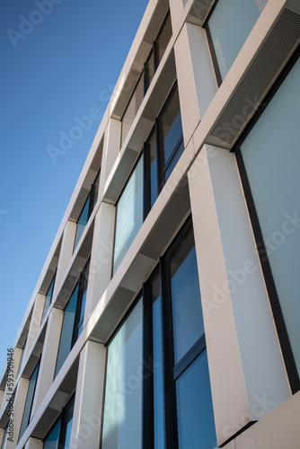 Facade of a multi-story building with white and blue elements and a blue sky