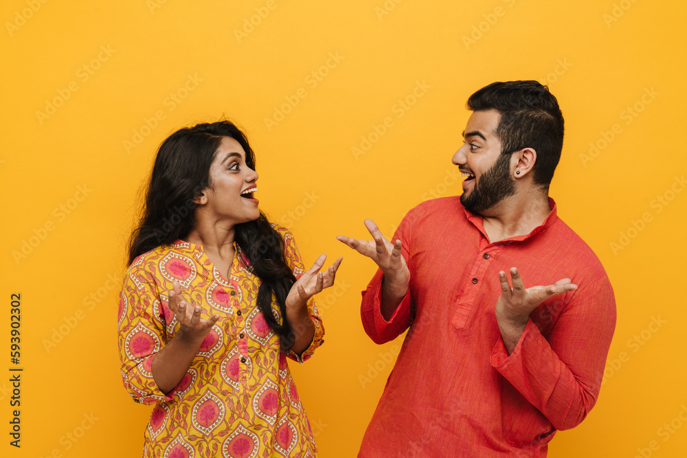 Surprised indian couple looking at each other and gesturing while ...