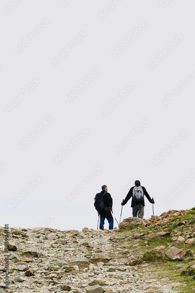 Friends hiking in mountains with backpacks, enjoying their adventure. Hiker on the top of a mountain standing still observing the landscape.active lifestyle.Space for text.
