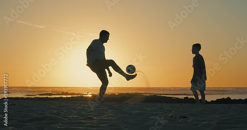 Father and Son playing football on the beach, family fun outdoors players in soccer in dynamic action have fun playing football, summer day under sunlight.