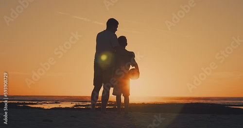 Father and Son playing football on the beach, family fun outdoors players in soccer in dynamic action have fun playing football, summer day under sunlight.