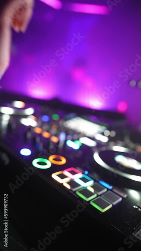 Vertical Video, Unrecognizable DJ Creates Dynamic Atmosphere on Dance Floor with Classic, Modern, and Remixed Tracks and Music, Mixing with Turntables in Nightclub and Neon Lighting. Slow motion