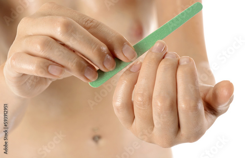Well-groomed young healthy woman at manicure filing fingernails with nail file photo