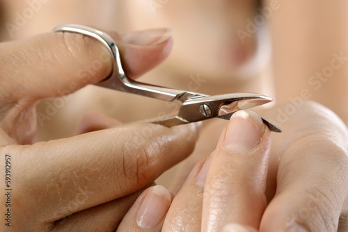 young healthy woman at manicure cuts fingernail with nail scissors 