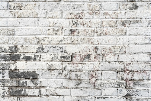Plain brick wall background with spots of gray in the worn white paint