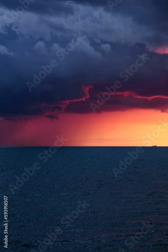 Vertical shot of a pink sunset at sea under dark clouds