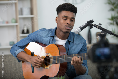soulful musician practicing guitar and singing into microphone