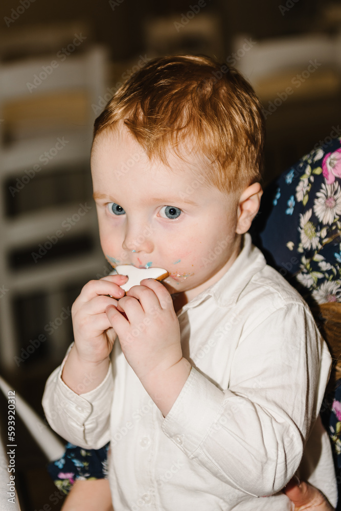 Сhild ate. The birthday boy is eating cookies with a cake. A cheerful child eats a sweet cake. A 2 year old boy celebrates his birthday in a restaurant. Serious facial expression. Closeup. Сhild ate. The birthday boy is eating cookies with a cake. A cheerful child eats a sweet cake. A 2 year old boy celebrates his birthday in a restaurant. Serious facial expression. Closeup.