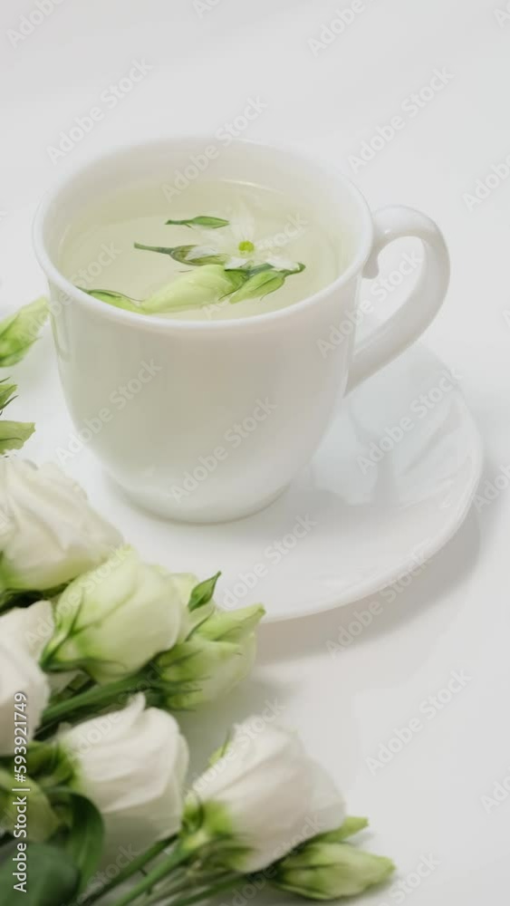Healthy herbal tea in a white cup with medicinal herbs, spring flowers and Chinese tea rose buds Mei Gui Hua for relaxation and wellness. Floral Infusion, vertical video Healthy herbal tea in a white cup with medicinal herbs, spring flowers and Chinese tea rose buds Mei Gui Hua for relaxation and wellness. Floral Infusion, vertical video