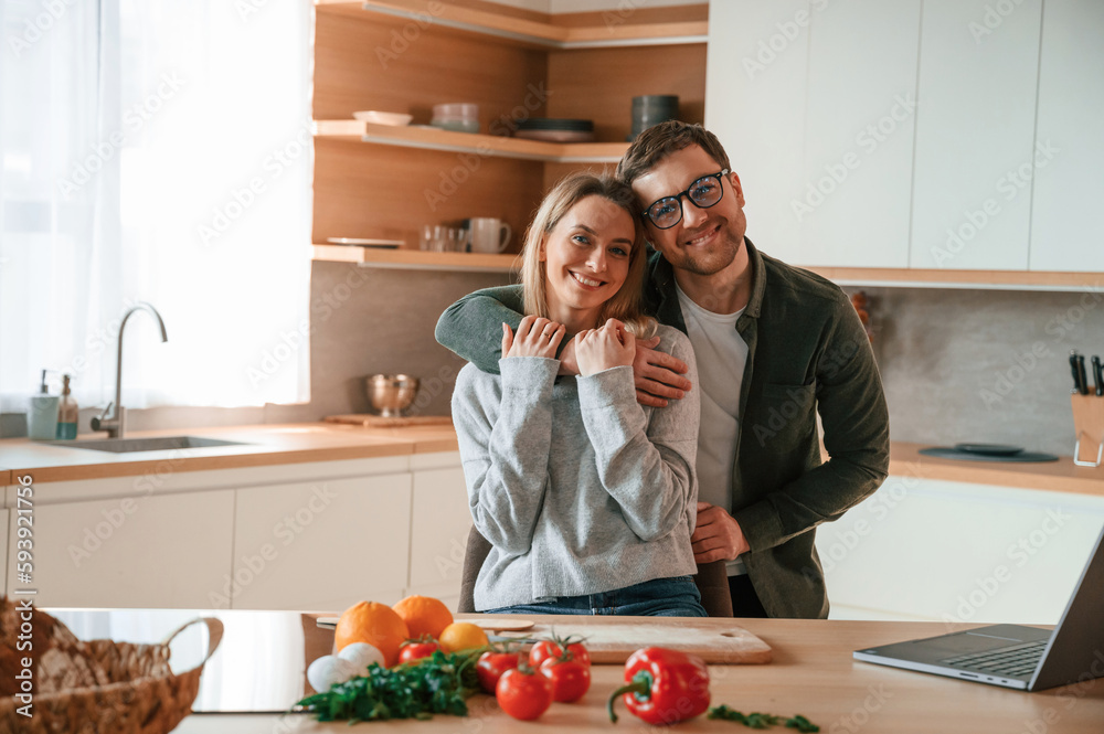 Embracing each other. Young couple is on the kitchen together Embracing each other. Young couple is on the kitchen together