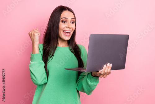 Photo of optimistic impressed woman straight hair dressed green sweatshirt win lottery yell hold laptop isolated on pink color background