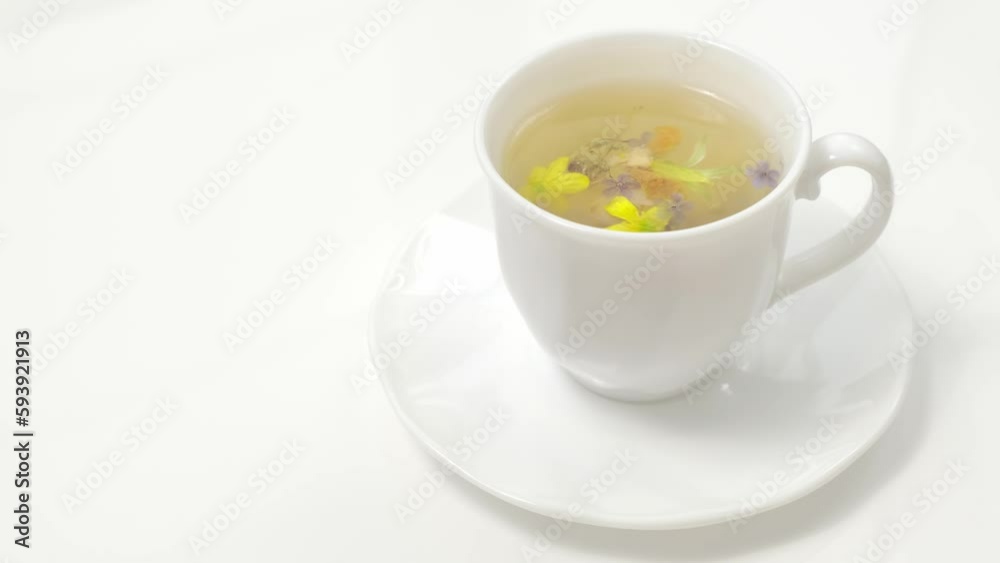 A white cup with fragrant herbal tea and flowers is the perfect choice for health and wellness. Tea time. Relaxing with herbal tea, white background A white cup with fragrant herbal tea and flowers is the perfect choice for health and wellness. Tea time. Relaxing with herbal tea, white background