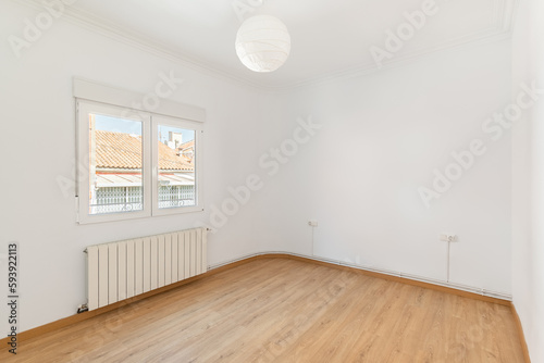 An empty small bright room with white walls and a window overlooking a neighbors house on a sunny day. The concept of housewarming in a new house. Copyspace