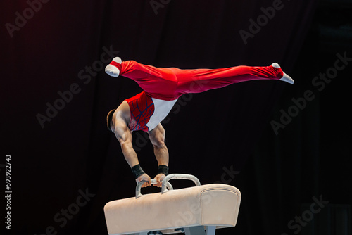 male gymnast performing on pommel horse competition artistic gymnastics, black background