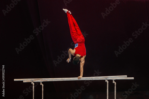 male gymnast performing on parallel bars competition artistic gymnastics, black background