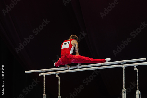 male gymnast exercise on parallel bars competition artistic gymnastics, black background photo