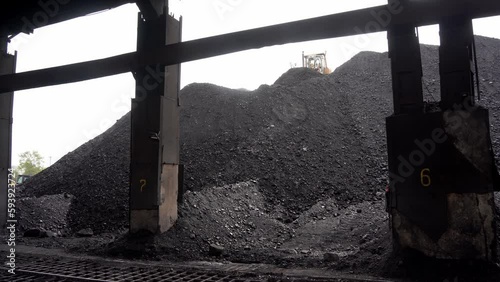 Almaty, Kazakhstan - 04.17.2023 : The tractor collects and unloads piles of coal at the heating plant. photo