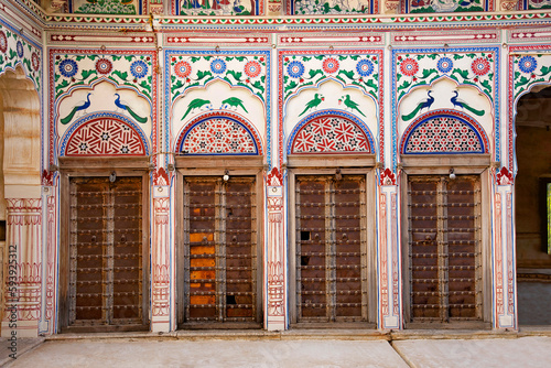 Colorful paintings and wooden windows on the outer wall of Seth Harmukhrai Sanehiram Chokhani Double Haveli, located in Mandawa, Shekhawati,  Rajasthan, India photo