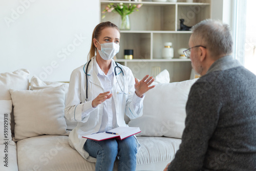 Female doctor examining older senior man in doctor office or at home. Old man patient and doctor have consultation in hospital room. Medicine healthcare medical checkup. Visit to doctor