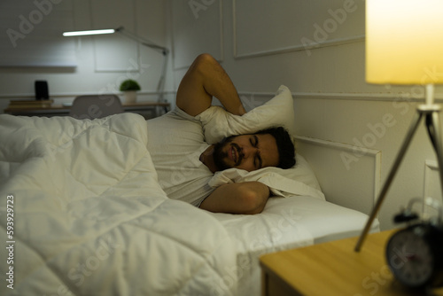 Stressed man trying to sleep with loud music