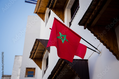Red flag of Morocco waving in the wind against blue sky background outside