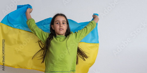 Child carries fluttering blue and yellow flag of Ukraine isolated on white. Ukraine s Independence Day. Flag Day. Constitution day. Girl in traditional embroidery with flag of Ukraine