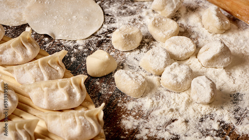 Scene of handmade dumplings with flour and pork filling on a wooden tabletop © wei