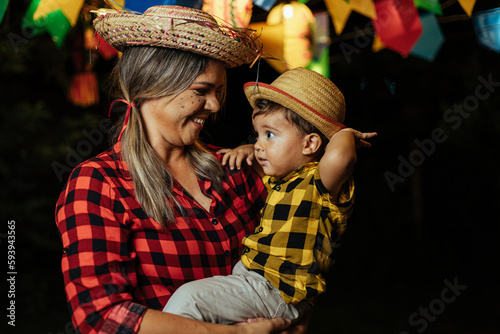 Mother and her baby son celebrating the Brazilian Festa Junina. Portrait of a woman and her son wearing typical clothes and a straw hat during the traditional June festival in Brazil.
