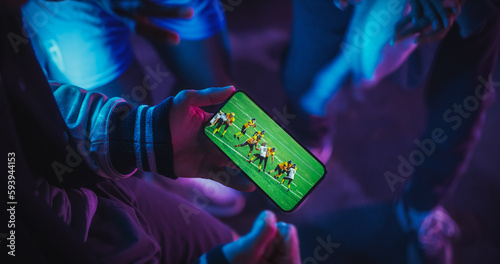 Close Up Smartphone Screen with a American Footabll Championship Live Broadcast. Group of People Using the Mobile Phone, Following a Sports Internet Stream, Supporting Their Rugby Team