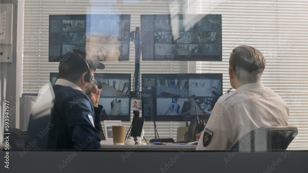Foto de Security officers sit in surveillance room and monitor CCTV