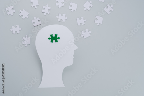 Concept of green business devotion, sustainability and negative impacts on the environment showing by paper-cut of human head with choice green puzzle on a gray background. flat lay