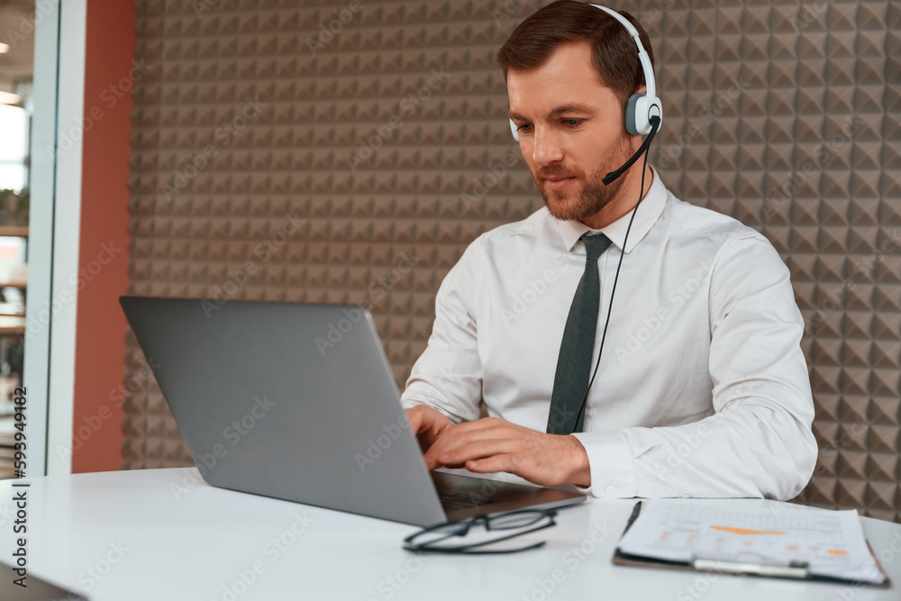 Using laptop. Handsome man in formal clothes is in the office Using laptop. Handsome man in formal clothes is in the office