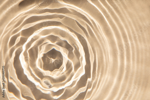 Abstract nature textured background, water waves in the pool with sun reflection. Clear water with bubbles and circles on beige background