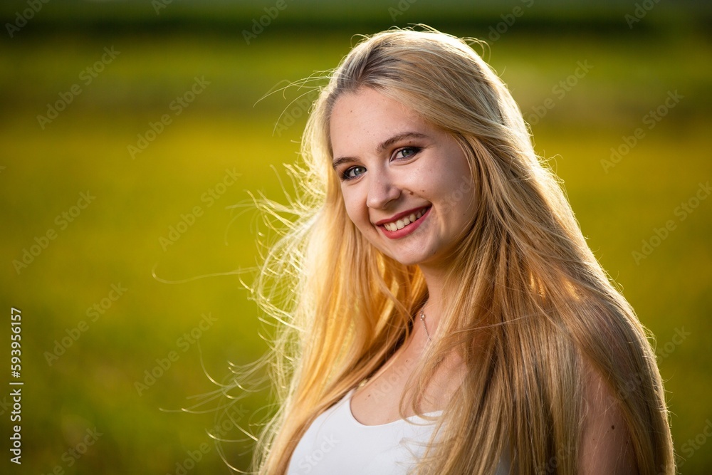 Caucasian blonde woman wearing a white dress posing in a wild nature