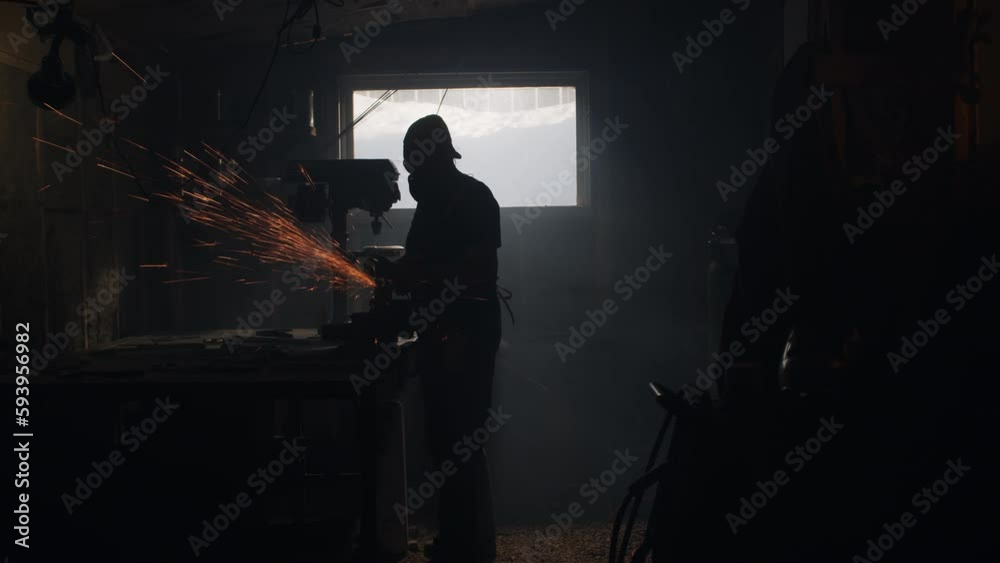Person grinds metal in a smokey workshop as sparks fly