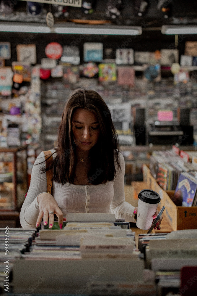 Young brunette woman girl in vintage record store holding coffee