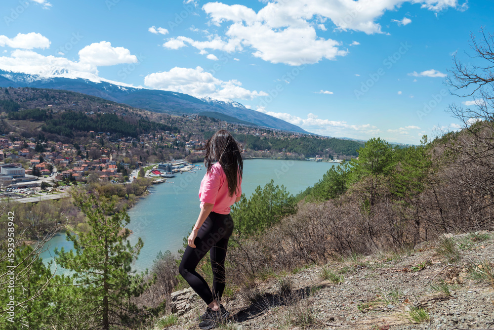 Naklejka premium Traveler woman standing high above a blue lake with stunning panoramic view .Traveling in the nature in Bulgaria 