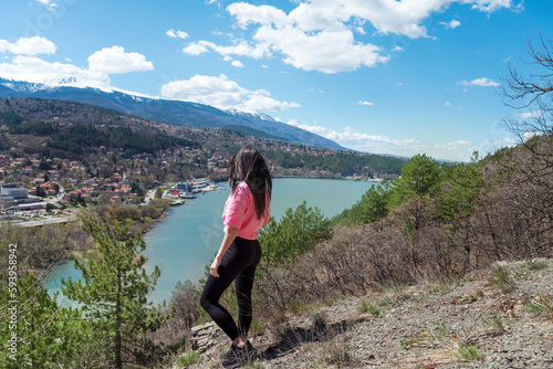 Traveler woman standing high above a blue lake with stunning panoramic view .Traveling in the nature in Bulgaria 
