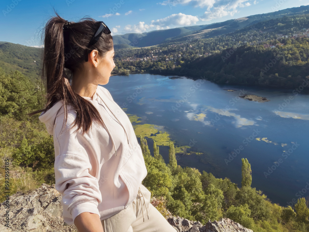 Traveler woman standing  high above a blue lake with stunning panoramic view .Traveling in the nature in Bulgaria 