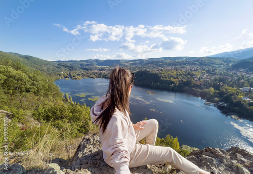 Traveler woman standing  high above a blue lake with stunning panoramic view .Traveling in the nature in Bulgaria  © boryanam