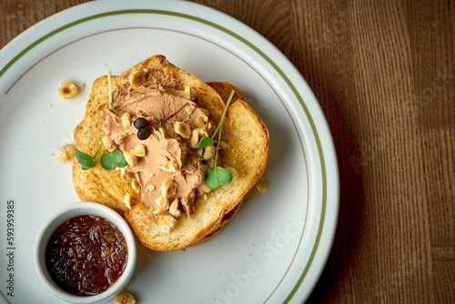 Toast with pate and nuts in a plate on a wooden background